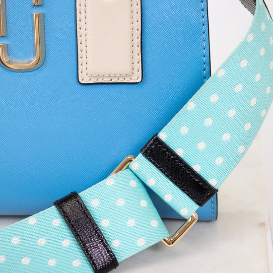 Blue handbag with a polka dot strap on a light background
