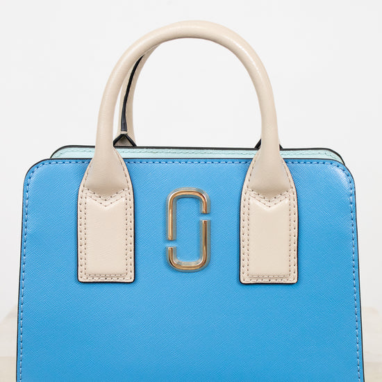 Blue handbag with beige handles and gold clasp on a white background