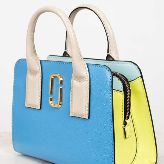 Color-blocked handbag with blue, yellow, and beige sections on a white background