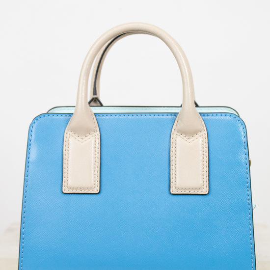 Blue handbag with white handles on a light wooden surface