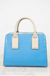 Blue handbag with white handles on a light wooden surface