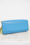 Blue bottom of purse with gold accents on a white marble surface