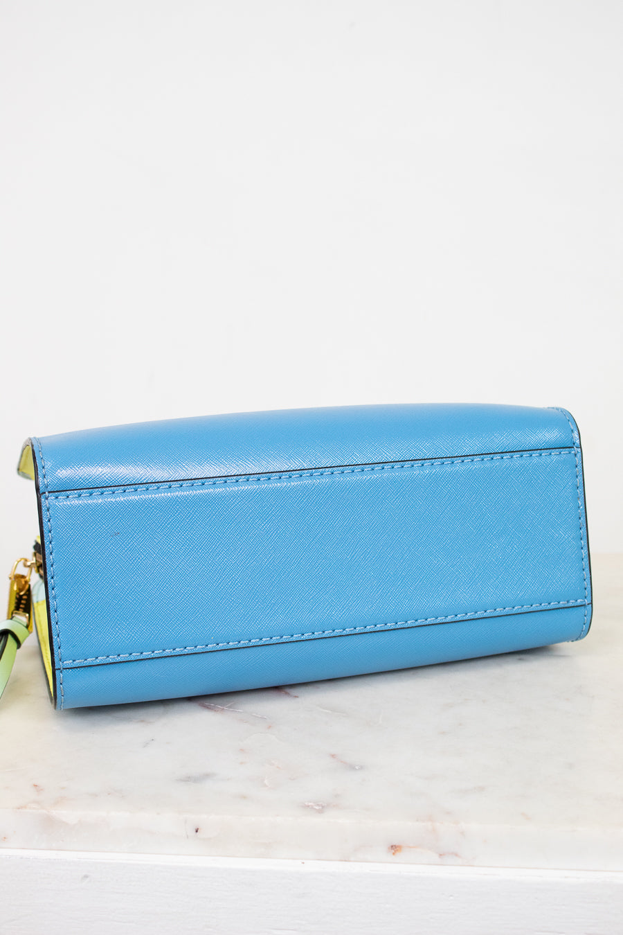 Blue bottom of purse with gold accents on a white marble surface