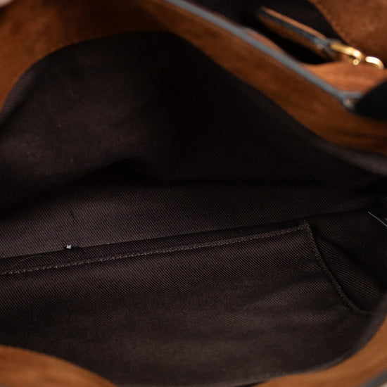Close-up of the interior of a brown suede or faux-suede handbag, showing a black fabric lining, interior pocket, and a small gold zipper pull.