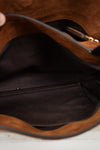 Close-up of the interior of a brown suede or faux-suede handbag, showing a black fabric lining, interior pocket, and a small gold zipper pull.