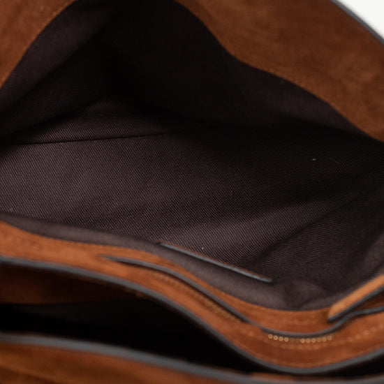 Close-up of the interior of a brown suede or faux-suede bag, showing a dark brown fabric lining and a zipper edge on a light surface.