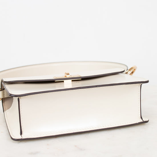Bottom view of shoulder bag with gold accents on a white marble surface