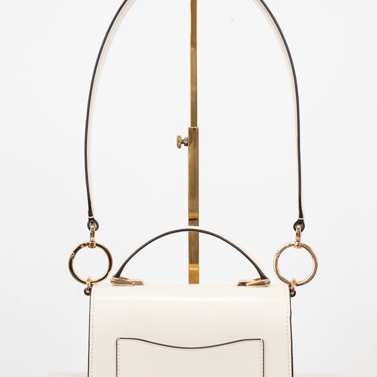 White handbag with gold accents on a white background