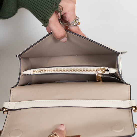 Open beige handbag held by a person with a plain background