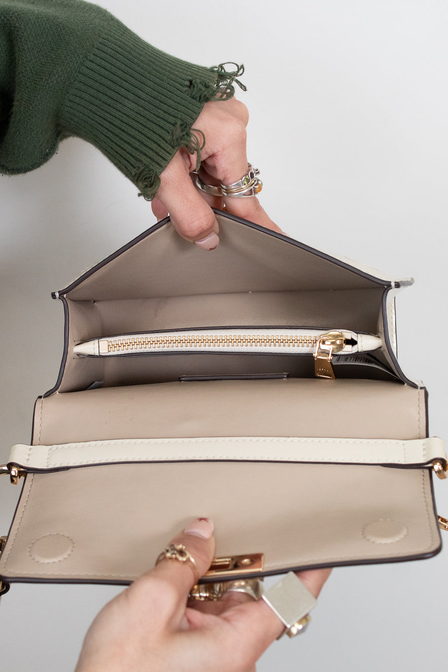 Open beige handbag held by a person with a plain background