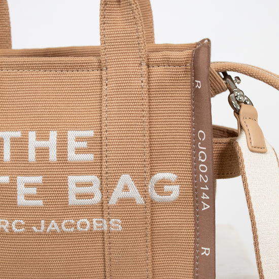 Brown handbag with 'The Tote Bag' Marc Jacobs text on a light background