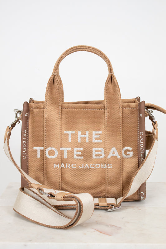 Brown tote bag with 'The Tote Bag' and 'Marc Jacobs' text on a white background