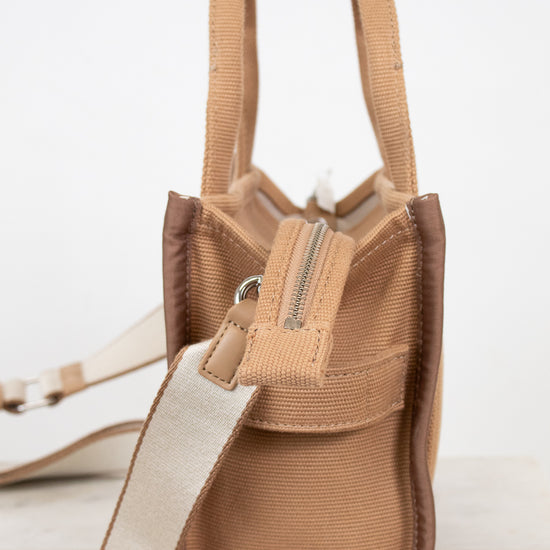 Brown side views of handbag with straps on a light background