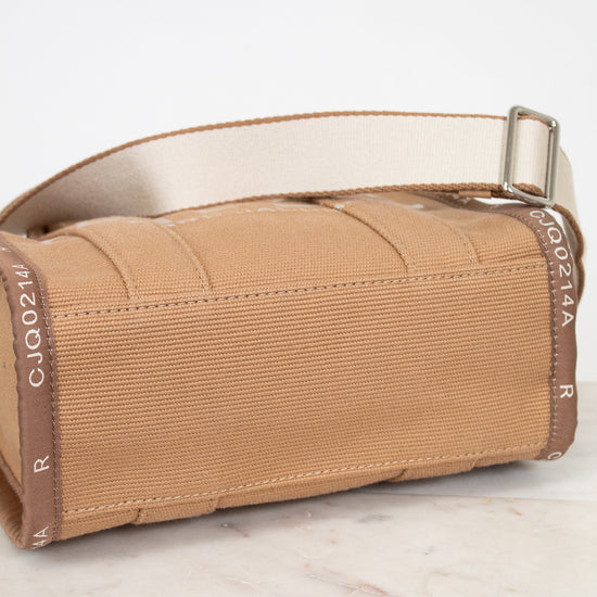 Brown bottom view of bag with a strap on a white surface