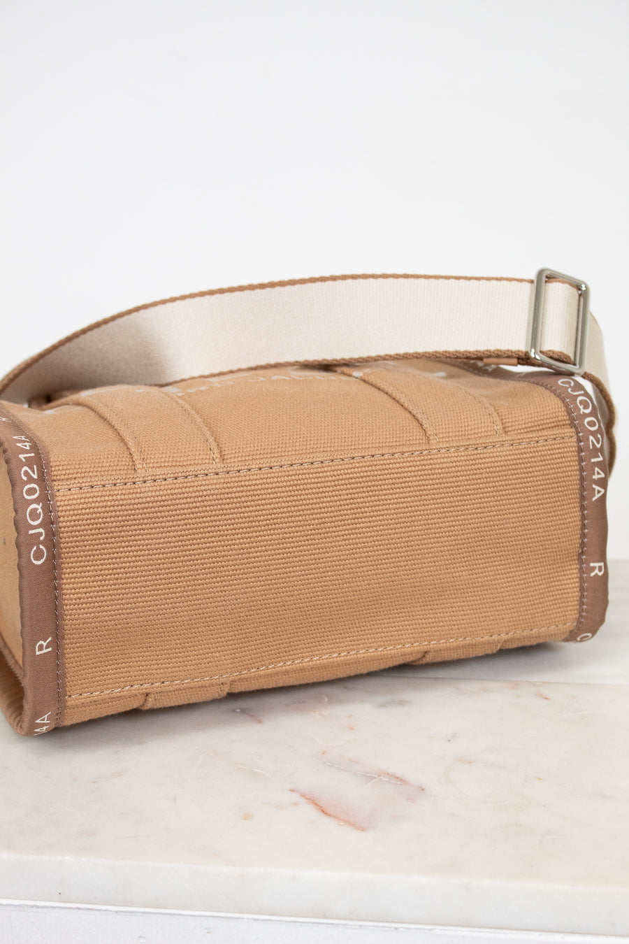 Brown bottom view of bag with a strap on a white surface