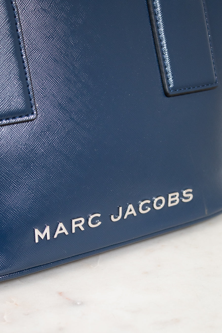 Blue handbag with 'Marc Jacobs' logo on a light background
