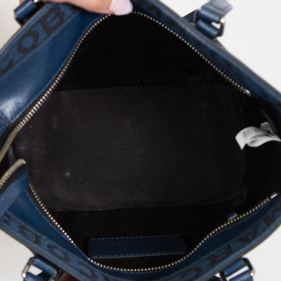 Blue handbag with a visible brand logo, held open by hands.
