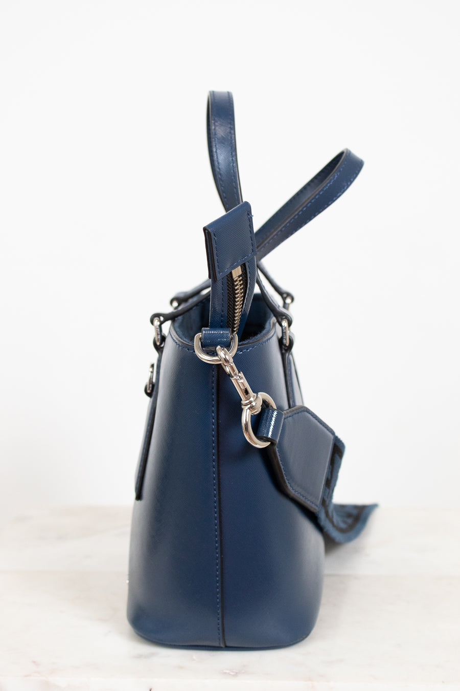 Navy blue leather handbag with a strap on a light background