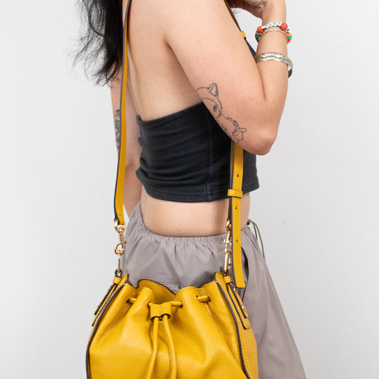 Person wearing a yellow handbag on a plain background