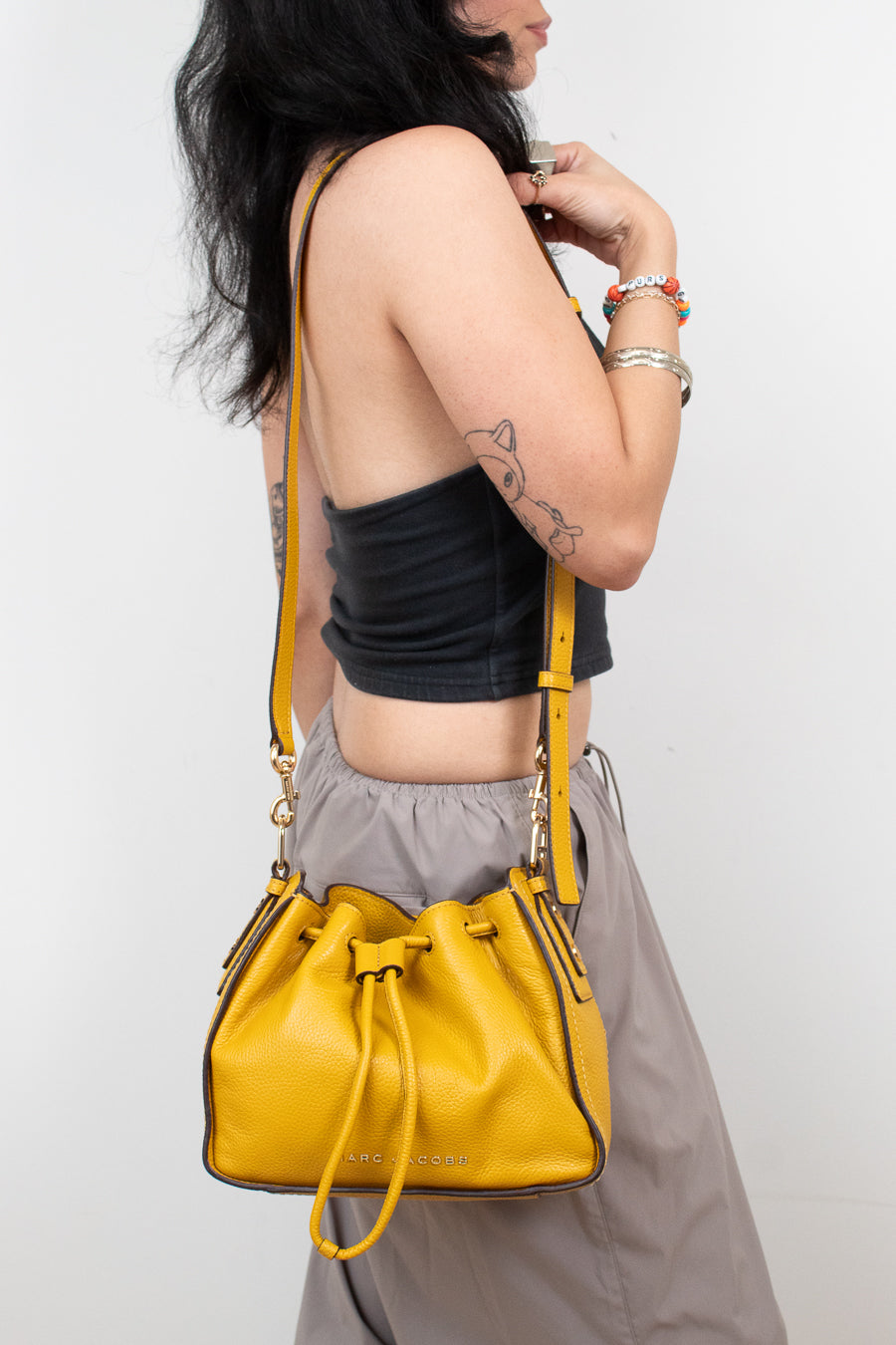 Person wearing a yellow handbag on a plain background