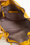 Close-up of interior of a yellow handbag with a visible brand logo on a white background