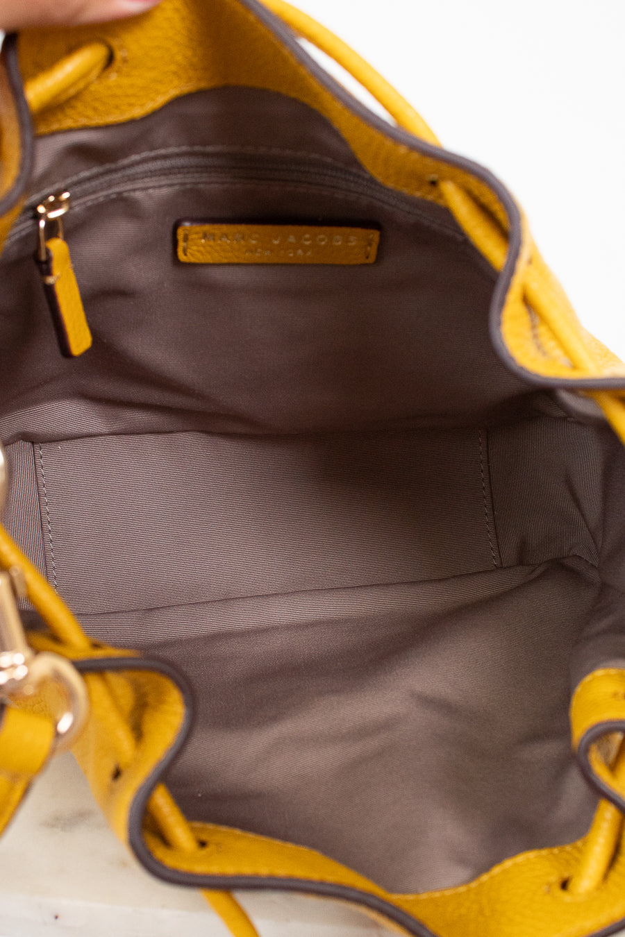 Close-up of interior of a yellow handbag with a visible brand logo on a white background
