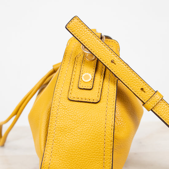 Yellow leather bucket bag with a strap on a light background