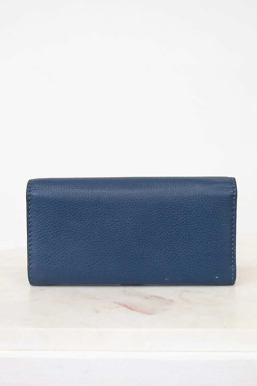 Back of Blue wallet on a white marble surface