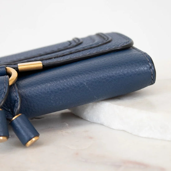 Blue handbag with gold accents on a marble surface