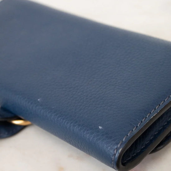 Blue leather wallet on a light marble surface