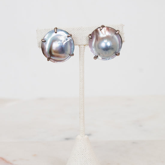 Pair of silver earrings on a white stand with a white background