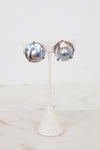 Pair of silver earrings on a white stand with a white background