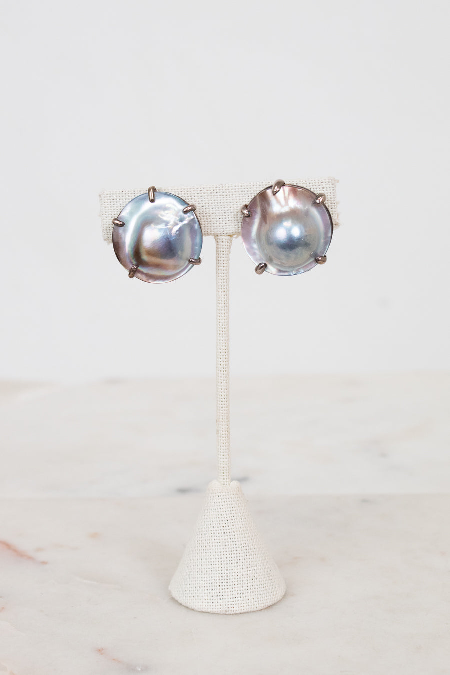 Pair of silver earrings on a white stand with a white background