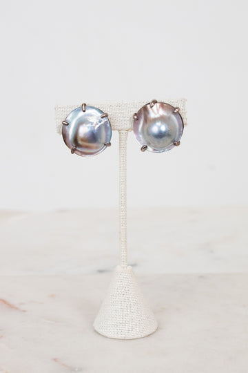 Pair of silver earrings on a white stand with a white background