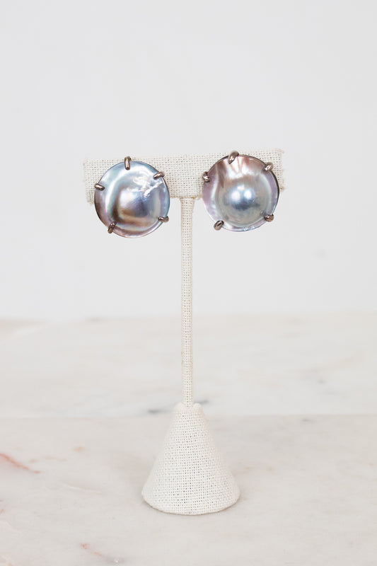 Pair of silver earrings on a white stand with a white background