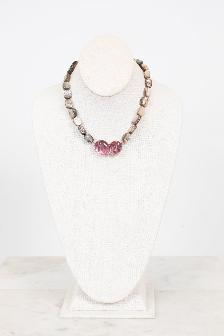 Necklace with mother of pearl beads on a white mannequin bust against a white background