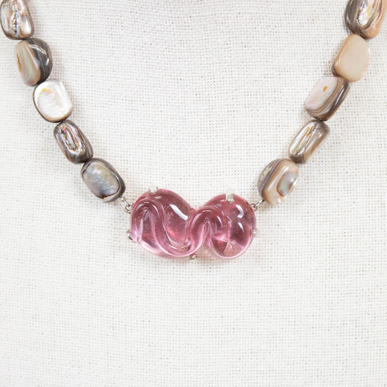 Necklace with pink glass bead and mother of pearl beads on a white background