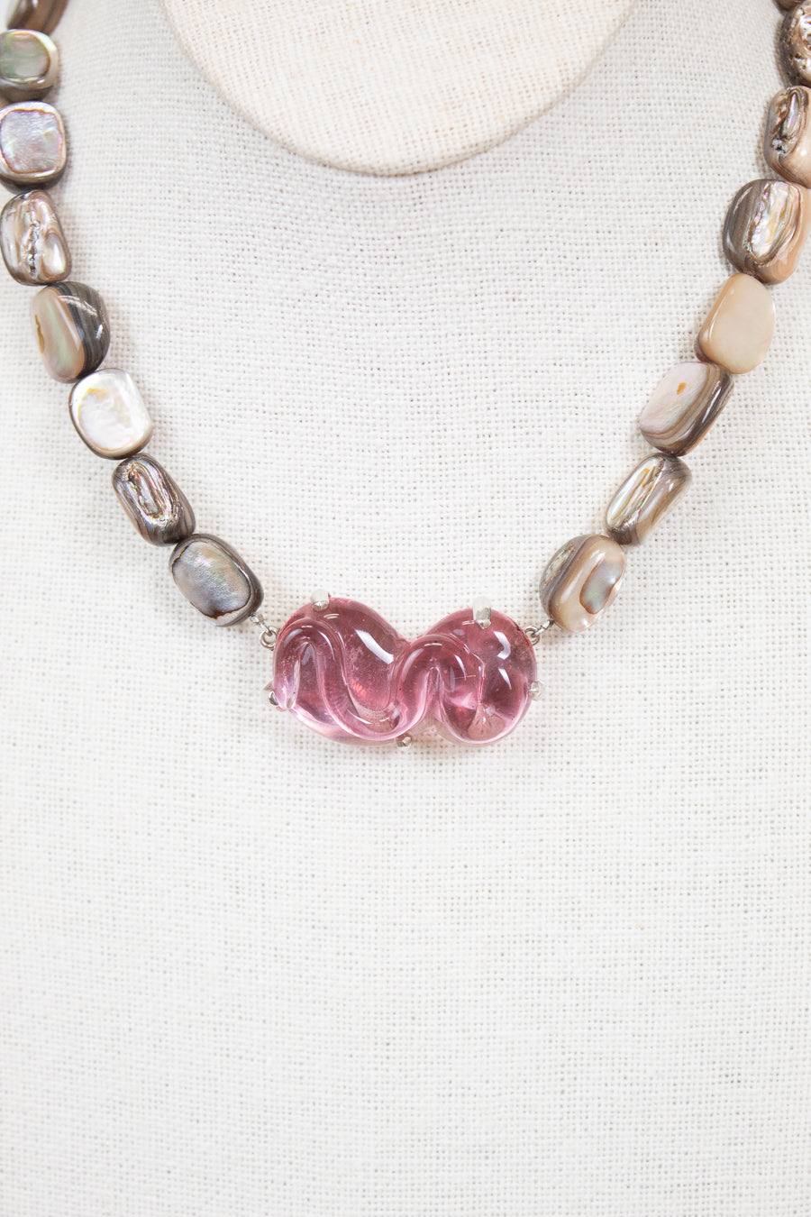 Necklace with pink glass bead and mother of pearl beads on a white background