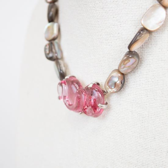 Necklace with pink beads and mother of pearl beads on a white background