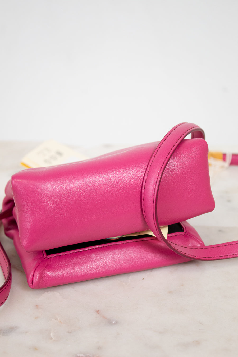 Pink handbag on a marble surface with a white background