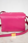 Pink handbag with a gold clasp on a light background