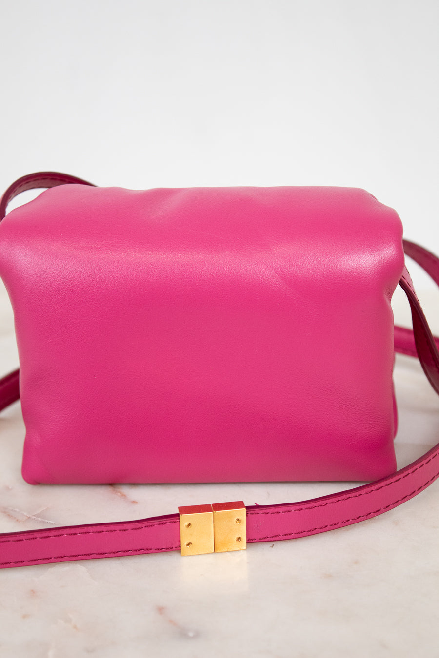Pink handbag with a gold clasp on a light background