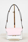 A structured shoulder bag with a light pink flap and a white body, featuring a black leather strap with gold-tone hardware, displayed on a minimalist stand.