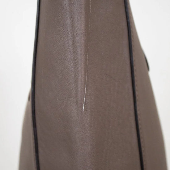 Side view of brown leather tote on white background