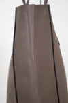 Side view of brown leather tote on white background