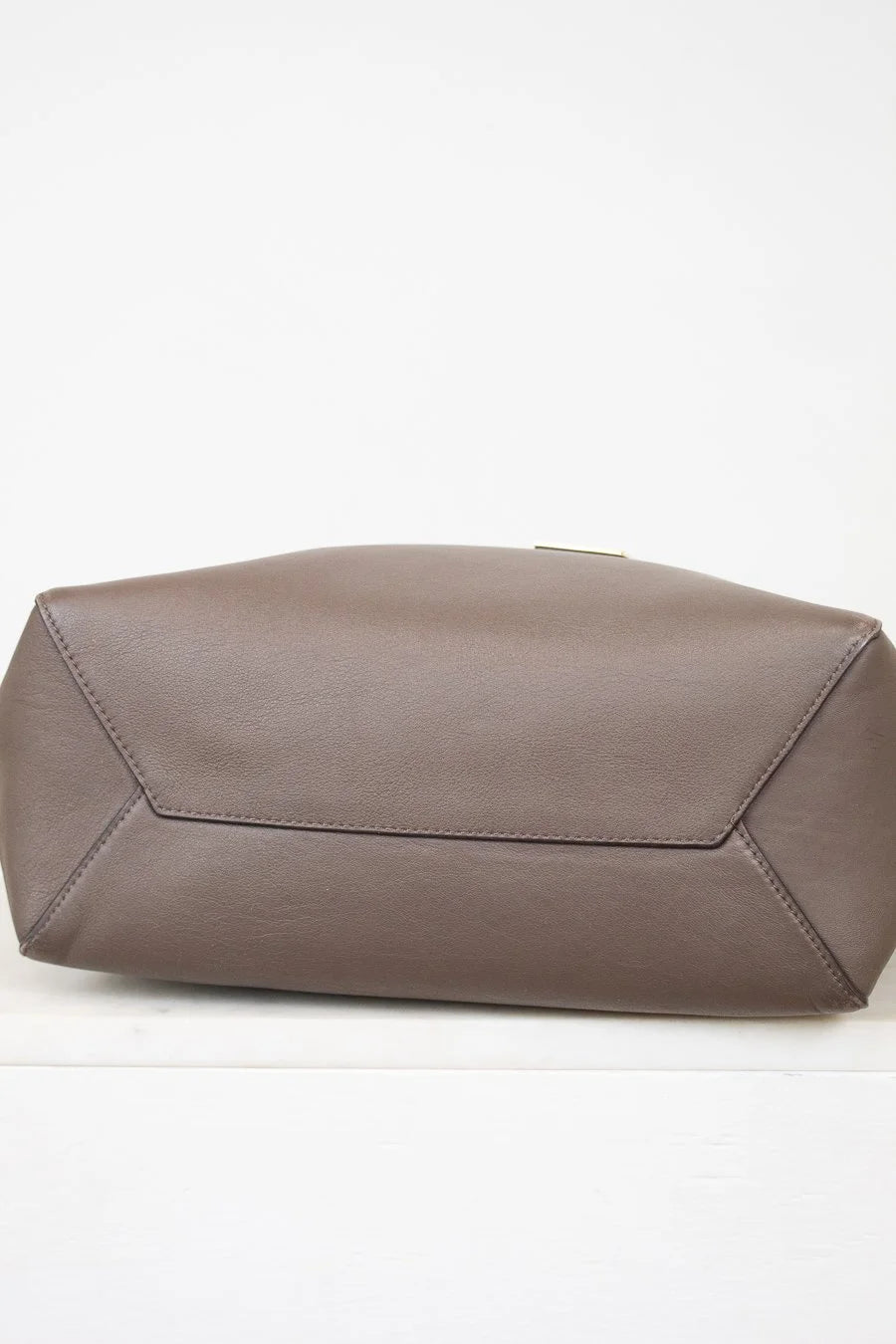 Bottom of brown leather tote on white background