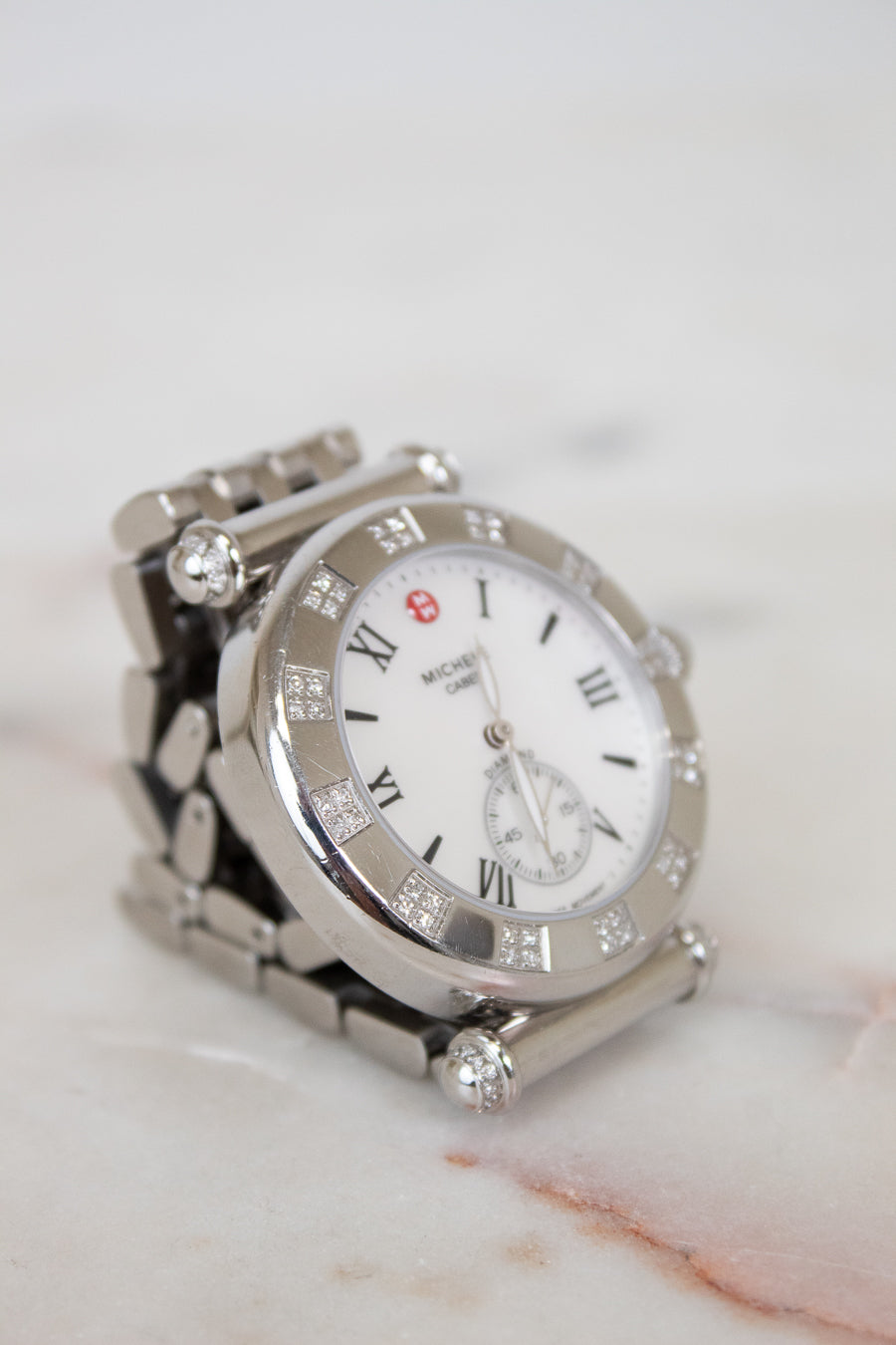 Silver watch with diamond accents on a marble surface