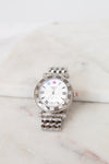 Silver watch with a white face on a marble surface