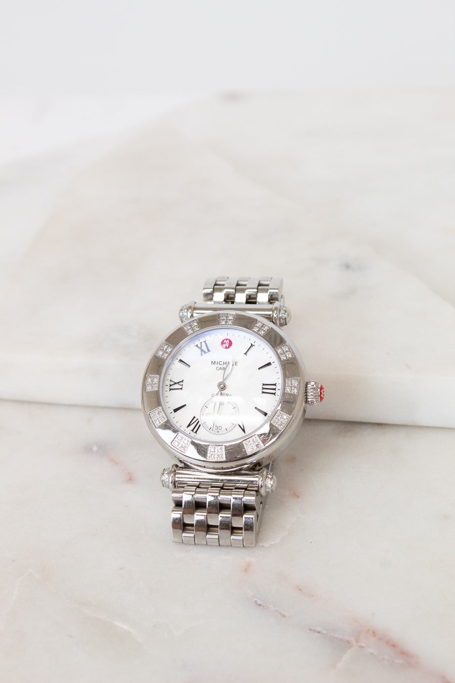 Silver watch with a white face on a marble surface