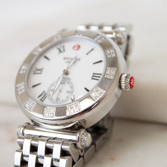 Silver watch with a white face on a light background